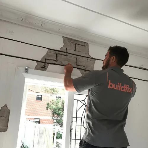 Buildfix technician carrying out structural repairs inside a home