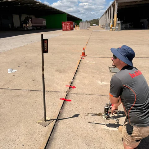 Buildfix technician injecting GeoPoly™ beneath the Bundamba hardstand slabs with the laser staff set up on the joint
