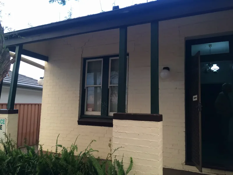 Front elevation of the Summer Hill doctor's surgery with cracks running from the window and verandah posts through the painted brickwork