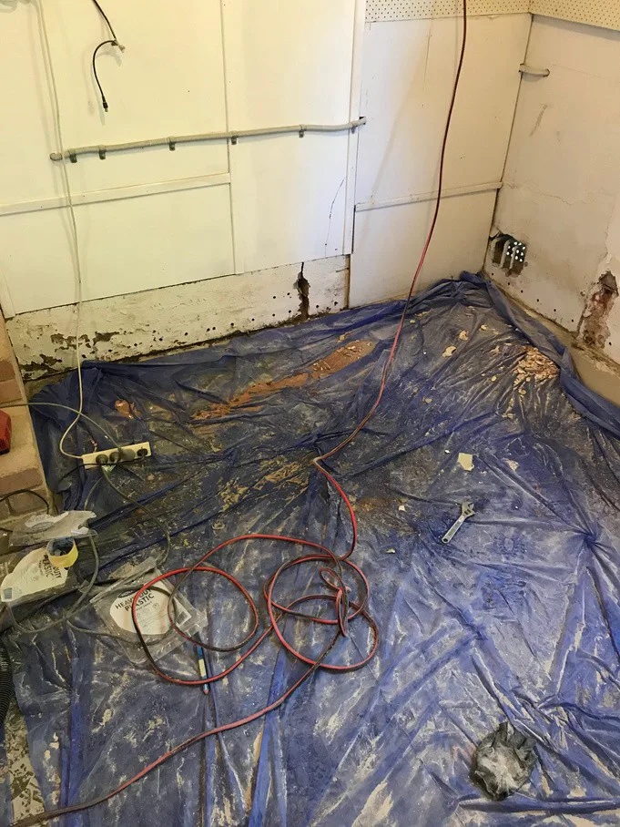 Interior wall at Frenchs Forest home showing damp damage with flaking paint and exposed brick at base