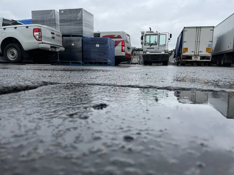Cracked, sunken loading slab at Cordina Farms in Girraween, NSW, with trucks and crates behind, before concrete relevelling