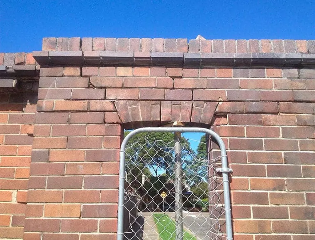 Cracked brick arch above the original turnstile gate of the heritage fairground wall