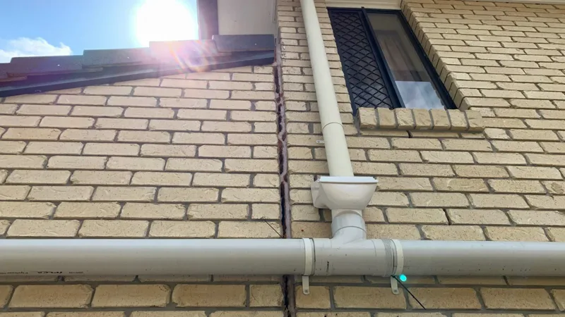 The open crack between the house and the extension running up the brickwork beside the downpipe before the lift