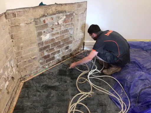 Buildfix technician injecting DampBlock cream into mortar course at base of exposed brick wall