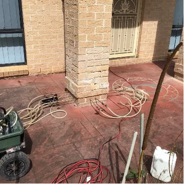 DampBlock injection equipment connected around base of brick balcony pillar at Prestons home