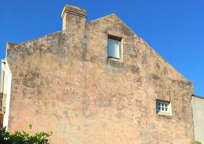 Degraded gable end wall of Victorian terrace in Rozelle with failing render and cracked brickwork