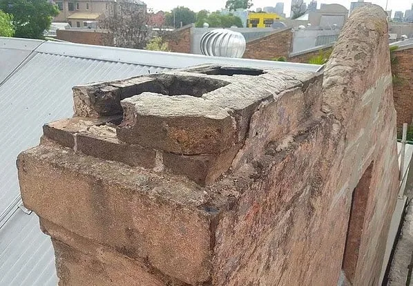 Damaged chimney and crumbling brickwork on Victorian terrace roofline in Rozelle