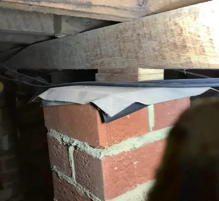 Brick pier under the Mosman living room floor with temporary wedges packed between the pier and the bearer