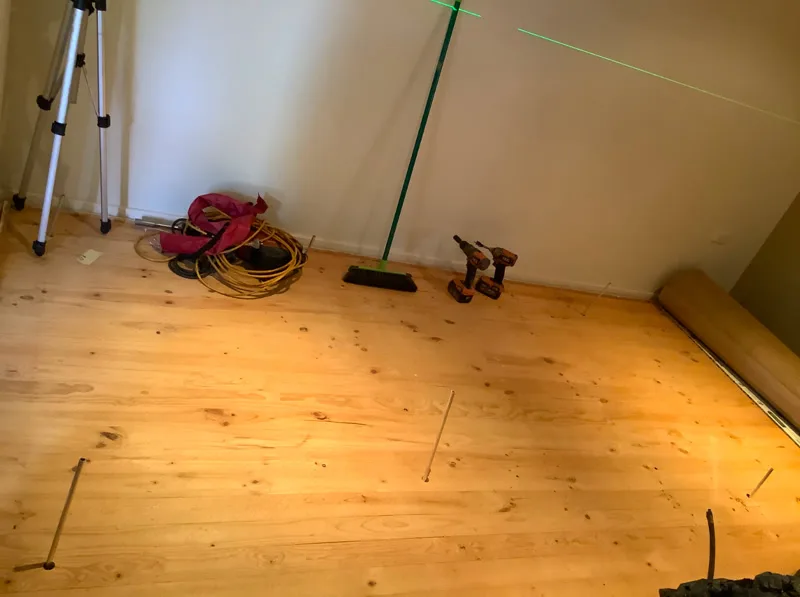 Living room with injection pipes and laser level during deep-lift repair