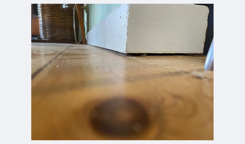 Floor dip visible at wall corner showing pier settlement beneath kitchen