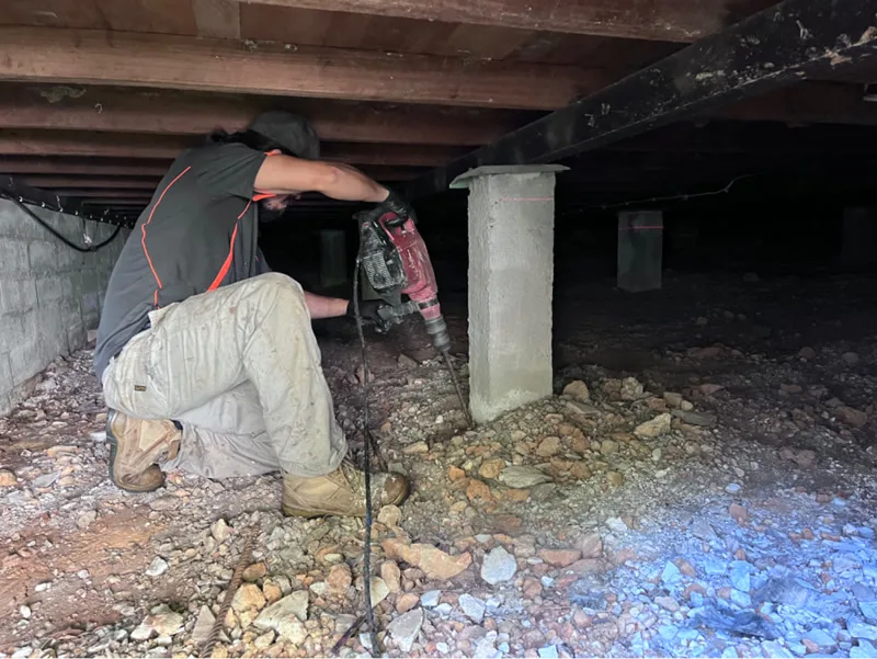 Buildfix technician drilling at concrete stump in subfloor