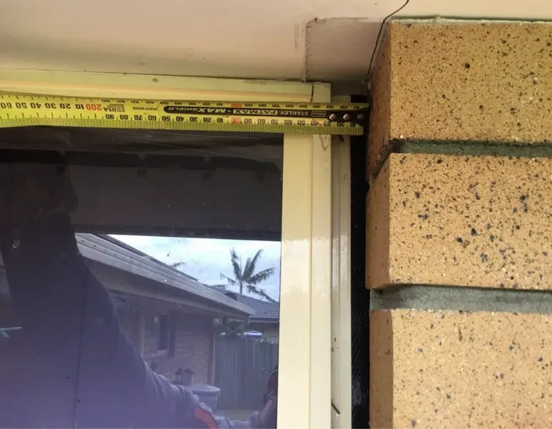 Tape measure across the gap that had opened between the window frame and the brick veneer of the Sunnybank Hills bungalow