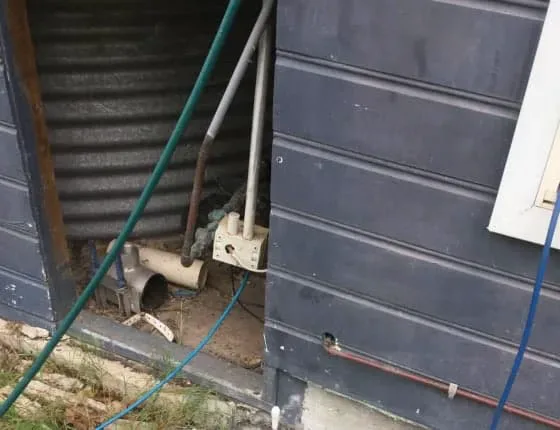 Broken drainage pipes and a disconnected downpipe at the base of the South Brisbane Queenslander's enclosed under-house wall
