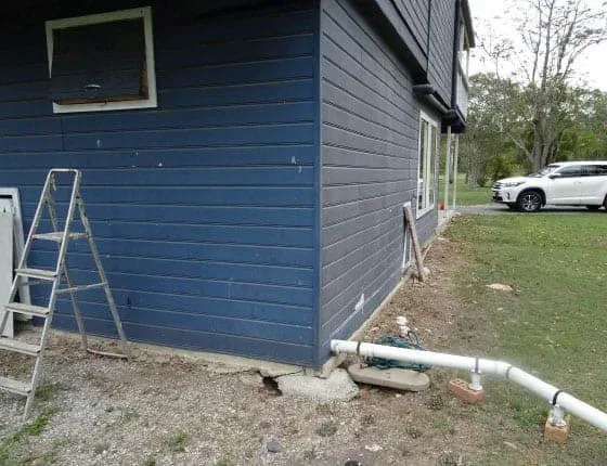 Corner of the South Brisbane Queenslander during the GeoPoly™ injection, with the ladder, pipes and the exposed concrete footing at ground level