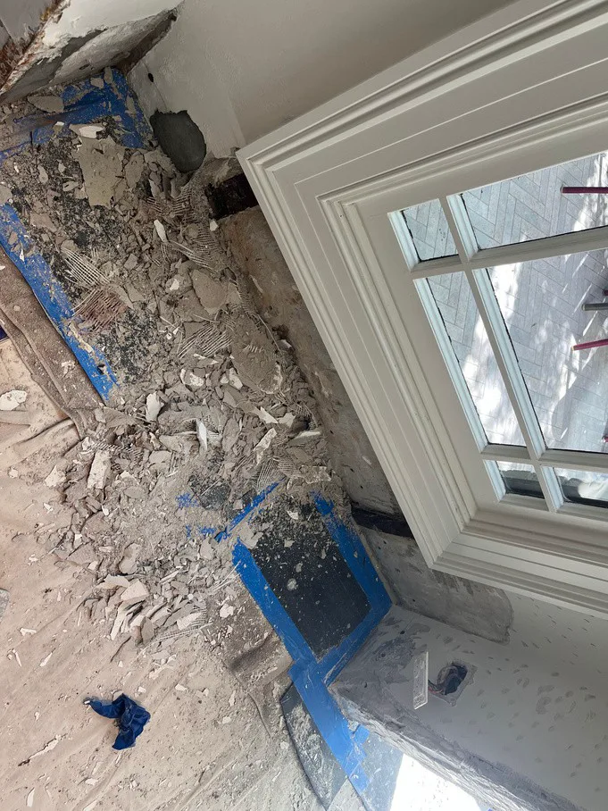 Stripped plaster and debris at base of terrace wall near bay window at Stanmore home