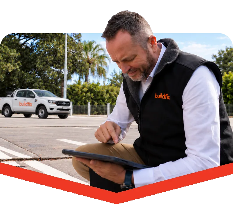 Buildfix engineer on a tablet beside laser levels on a commercial carpark