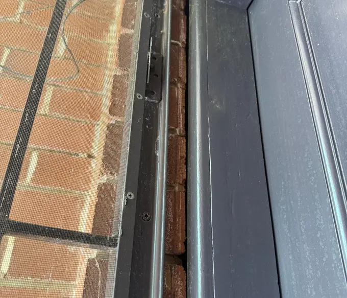 Gap between door frame and brick wall caused by wall leaning outward and detaching