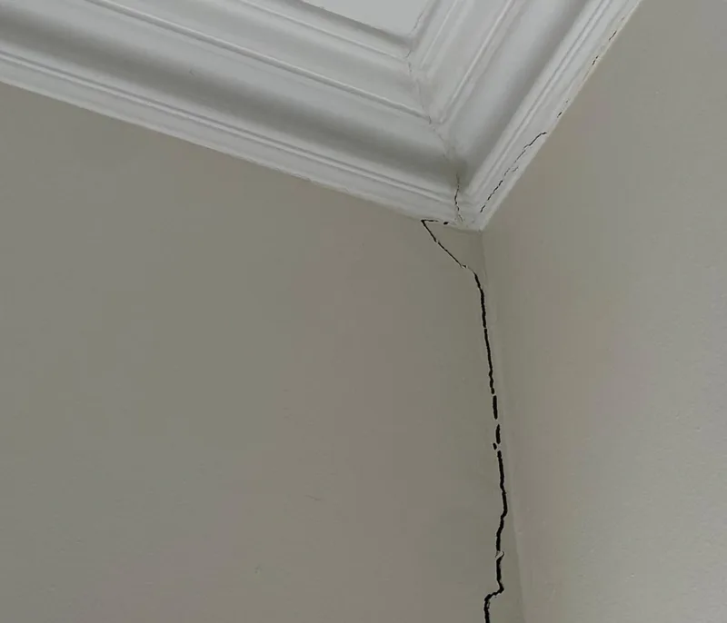 Vertical plaster crack running up the corner of an internal wall into the ceiling cornice