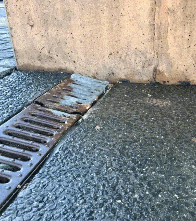 Same drainage grate relevelled and sitting flush against wall