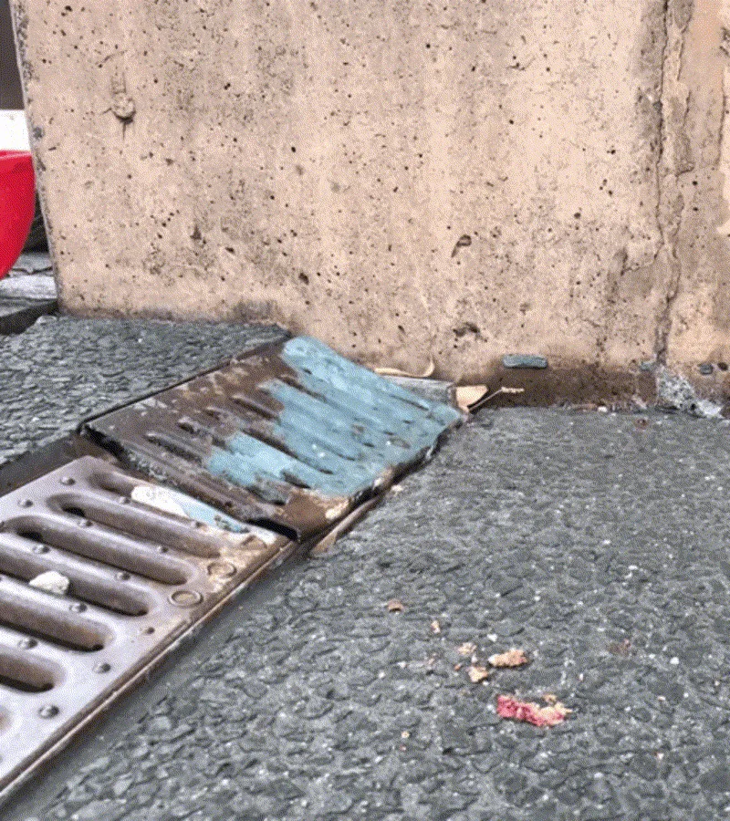 Drainage grate sunken away from retaining wall with visible gap
