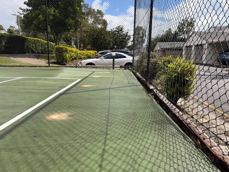 Settlement along edge beam and fence line of tennis court slab