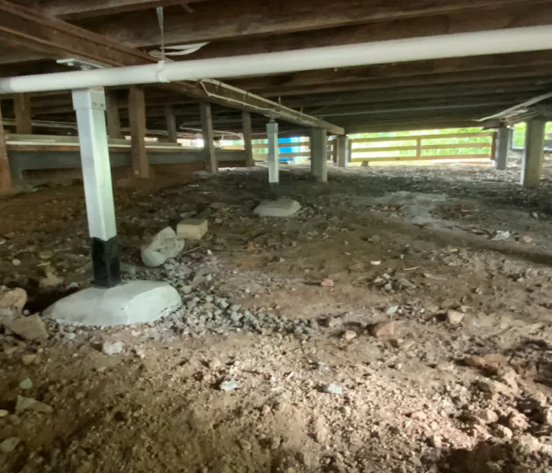 Sub-floor showing new steel piers installed on undersized concrete pads without addressing ground conditions