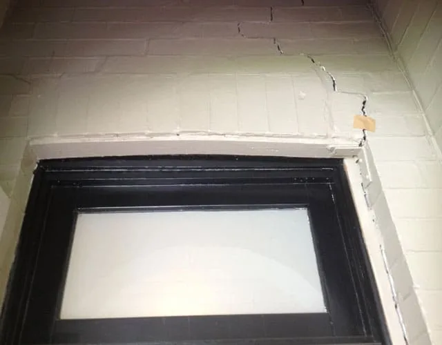 Rusted steel lintel above a window pushing the brickwork apart