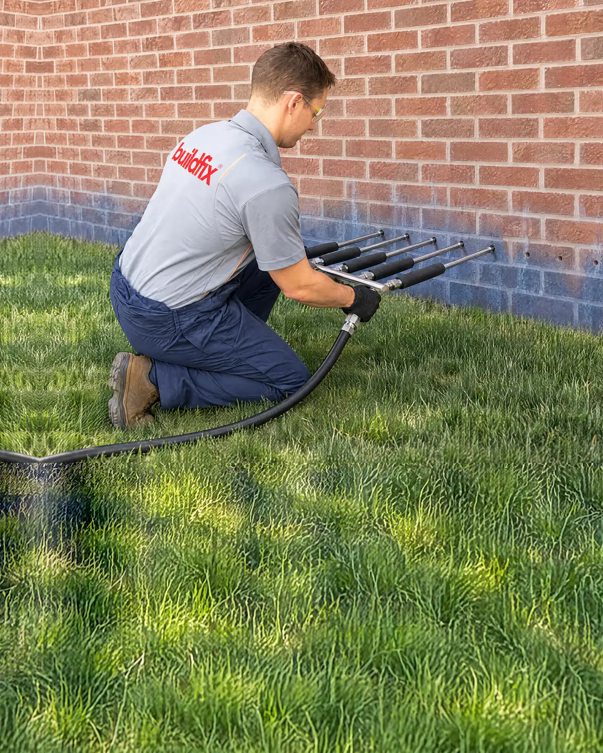 DampBlock resin injection equipment treating rising damp at base of brick wall