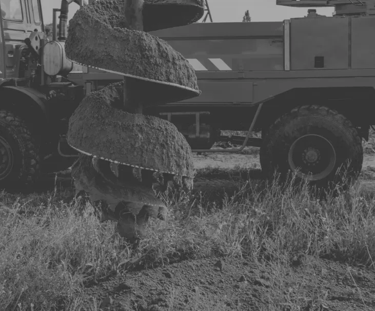 Helical screw pile being driven into the ground for foundation repair