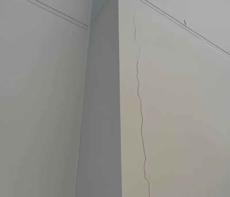 Vertical crack running down internal wall corner caused by brick expansion over decades