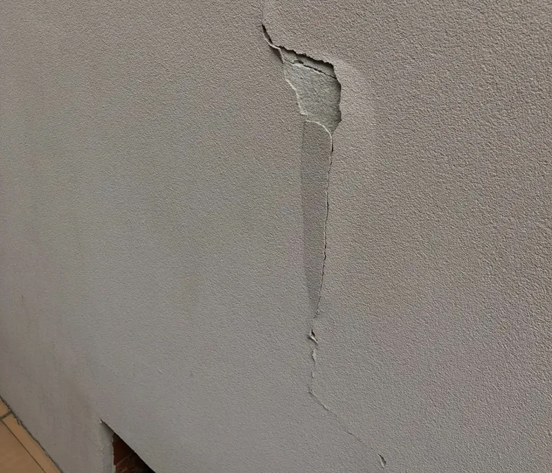 Vertical crack with paint and render lifting off internal wall caused by heave movement