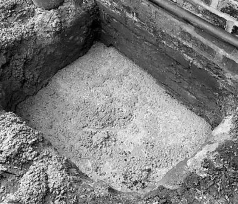 Mass concrete poured into excavated pit beneath brick wall footing for underpinning