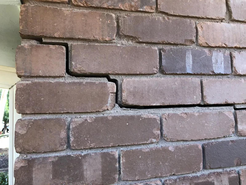 Staircase crack in dark brick wall with shifted bricks at CSIRO