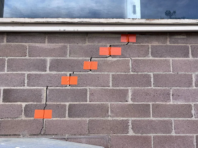Same staircase crack marked with orange tape — wider angle