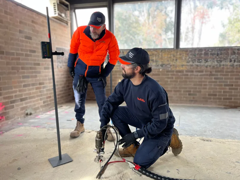 Two Buildfix workers injecting resin through concrete floor at CSIRO