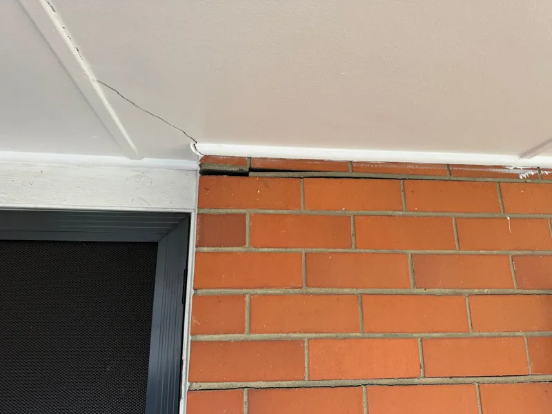 Crack between ceiling cornice and brick wall above door