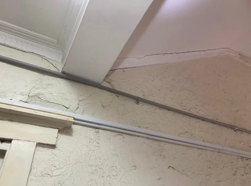 Interior ceiling and wall cracks in plaster with cornice damage