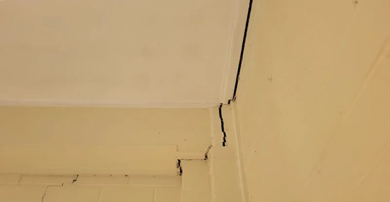 Interior ceiling crack at wall-ceiling junction — before
