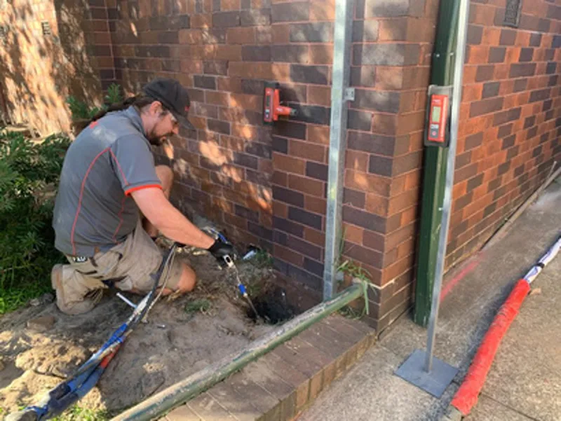 Worker injecting resin at foundation of apartment block