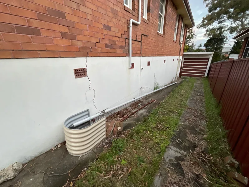 Side of house showing vertical crack in render and brick wall