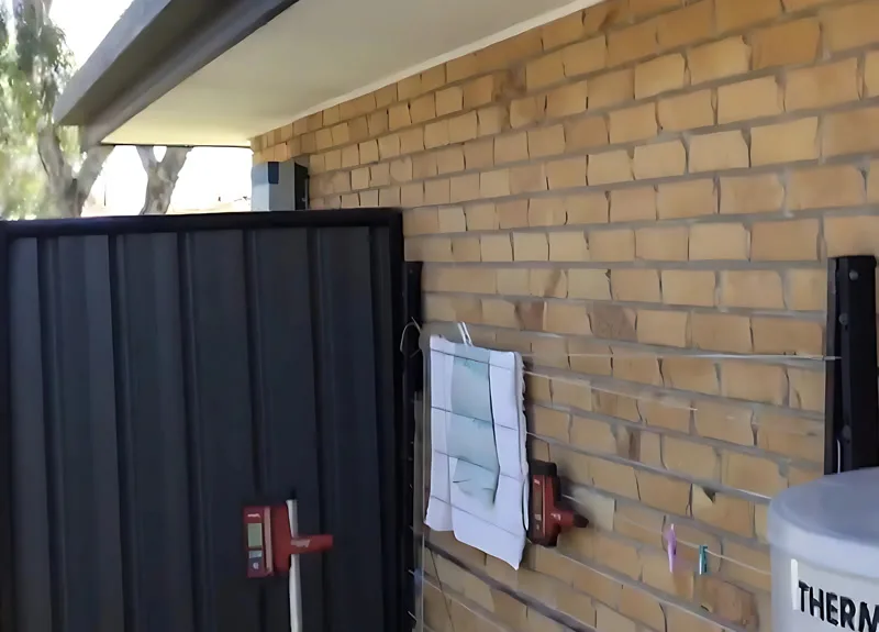 Side of buff brick house with laser receiver and gate