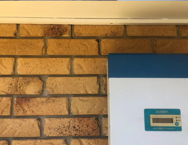 Same brick wall near eaves with solar inverter — no crack — after