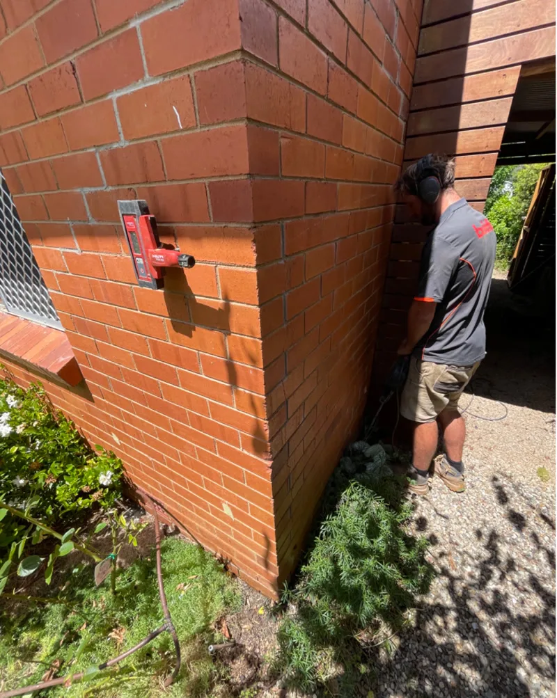 Worker with laser receiver checking level on brick corner