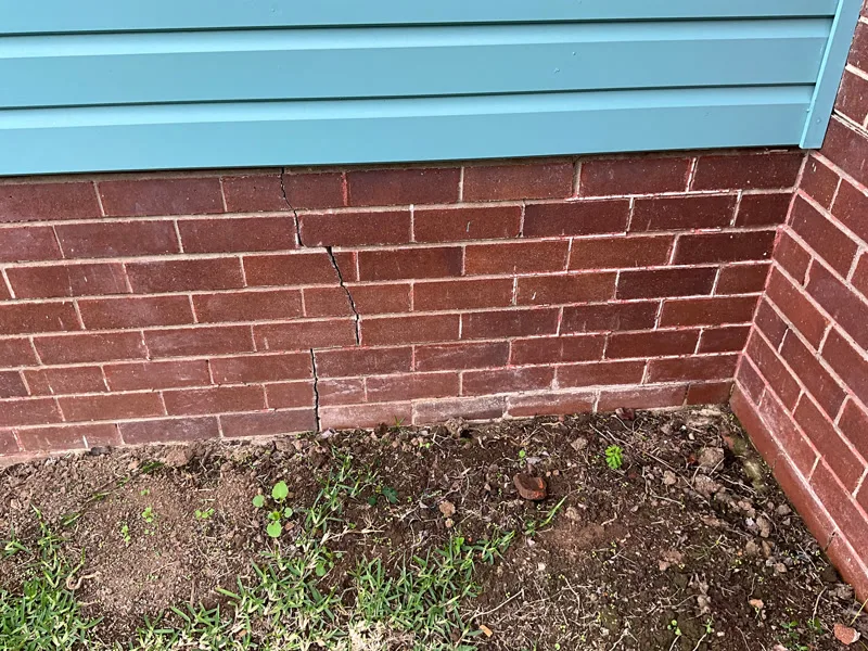 Vertical crack in brick wall near ground level
