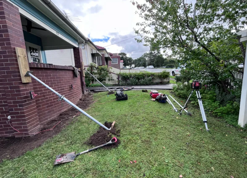 Resin injection setup on front lawn with laser level and pole
