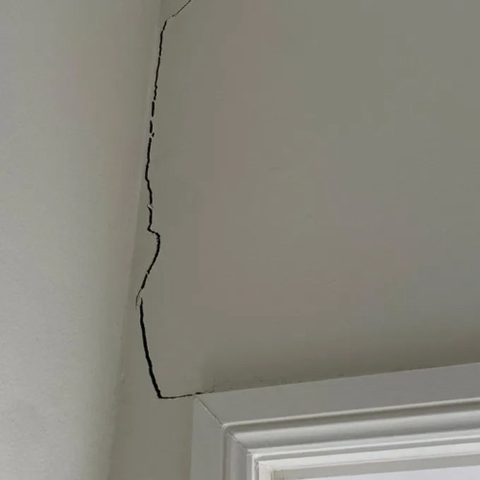 Diagonal cracks radiating from the corner of a window frame due to foundation movement