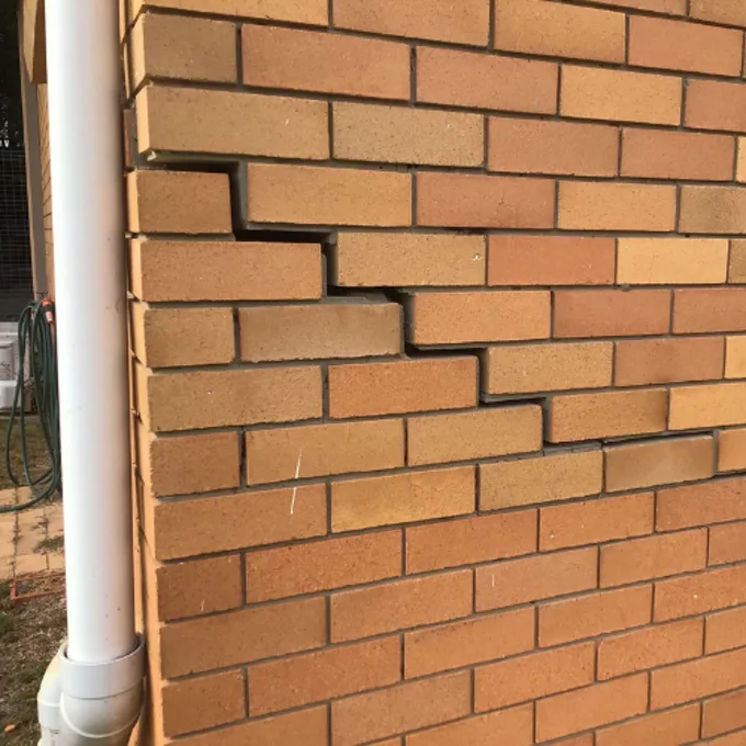 Stepped cracks following mortar joints in brick wall indicating foundation movement