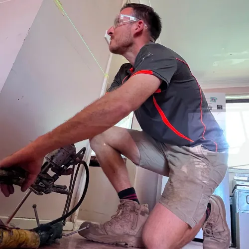 Buildfix technicians injecting GeoPoly resin beneath indoor concrete slab to fill voids and lift the floor