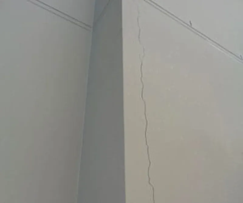Vertical crack running down an internal plaster wall corner from ceiling to floor