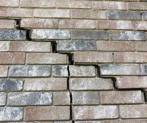 Stepped brick wall cracks following mortar joints indicating foundation movement